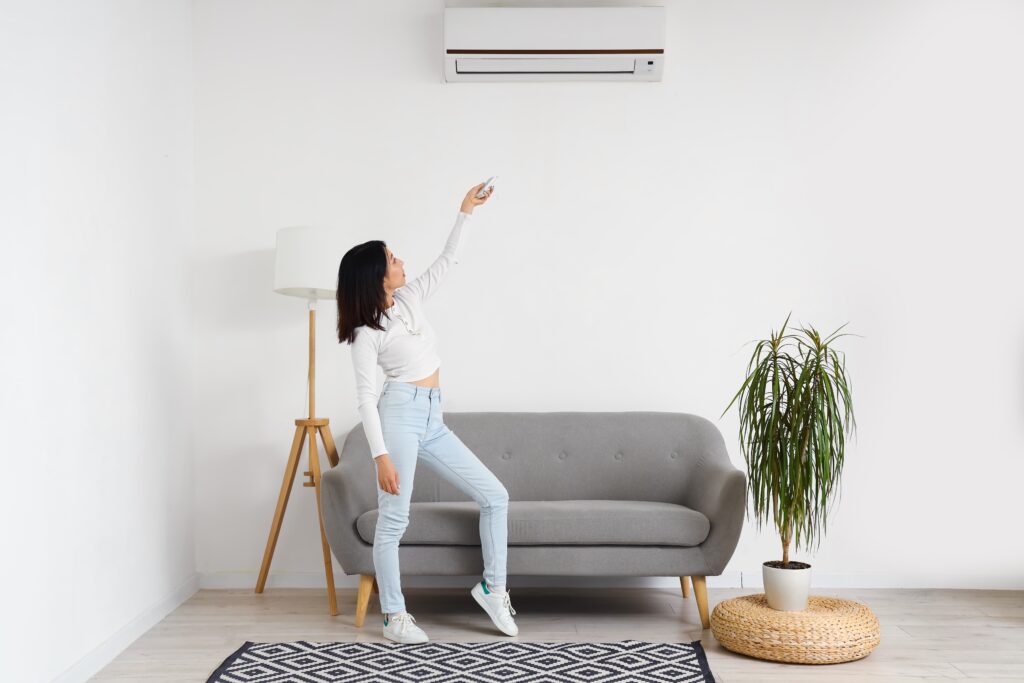 Beautiful,Asian,Woman,Switching,On,Air,Conditioner,At,Home